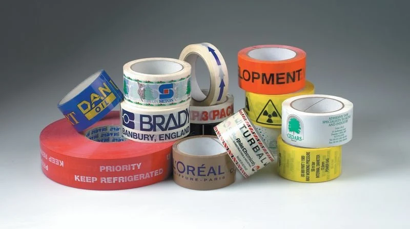 Several rolls of packing tape in different colours with printed logos and text.