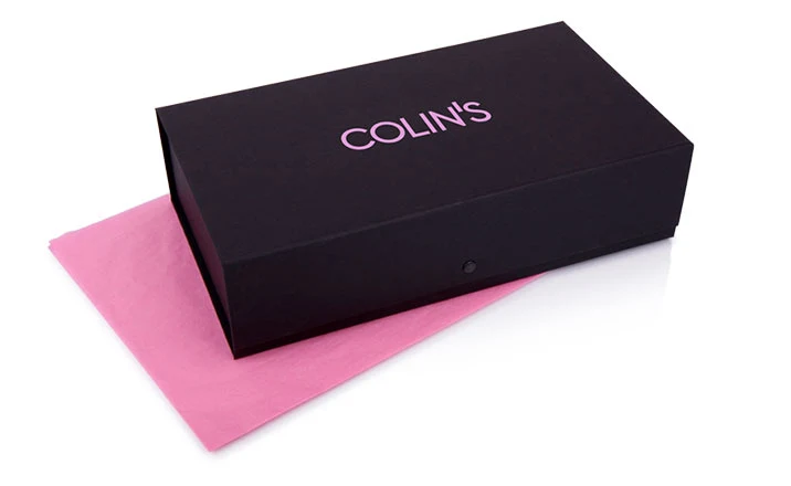Mörk rektangulär premiumlåda med ljus logotyp, placerad på rosa papper.